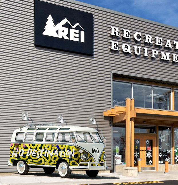 A 'No Destination'-wrapped vintage VW bus parked outside an REI Co-op storefront